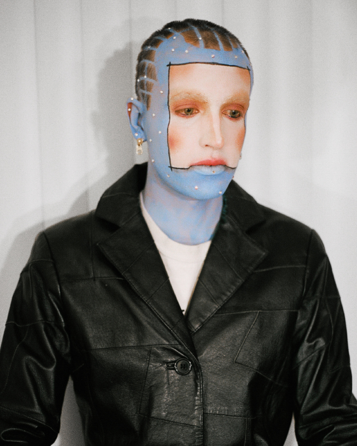 Jesse in graphic blue, cream and red face paint against a white background
